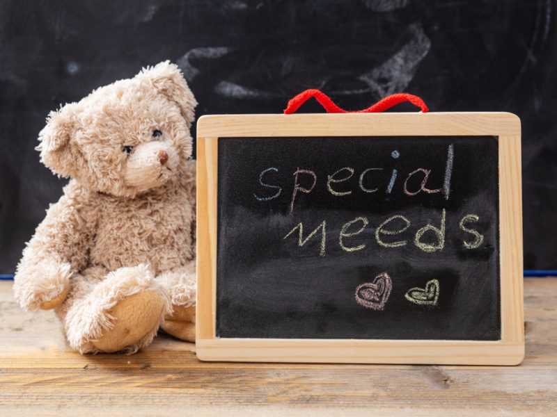 Special Needs Teddy bear sitting next to a small chalkboard with the words ‘special needs’ written in chalk.