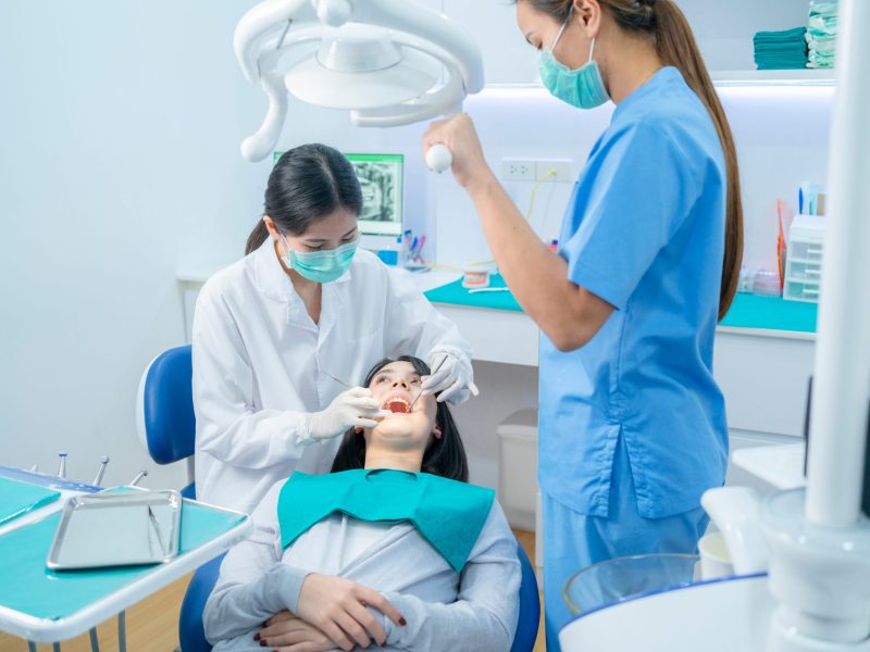 Dentist performing dental treatment with assistant assisting patient