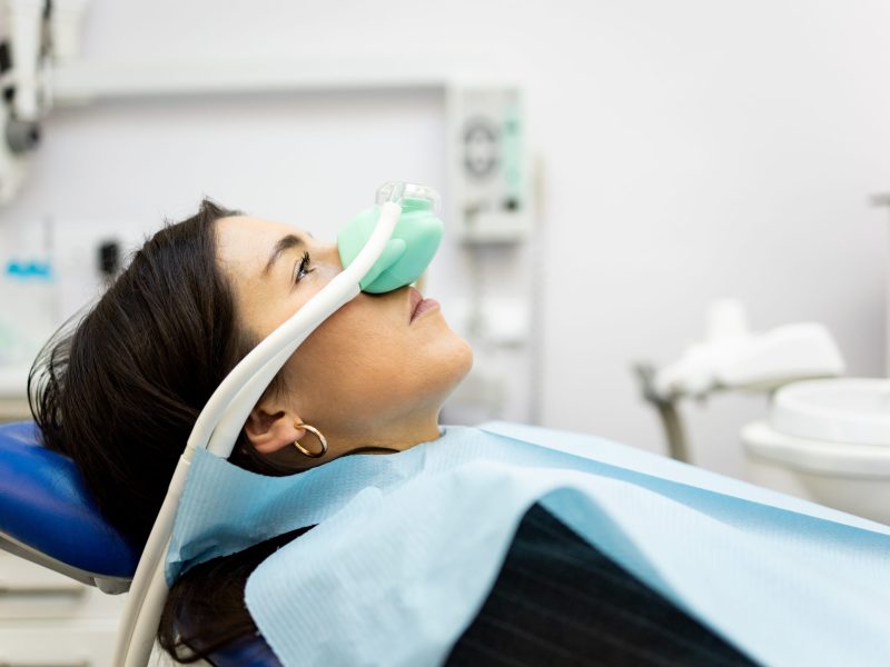 Patient wearing a laughing gas mask while lying in a dental chair
