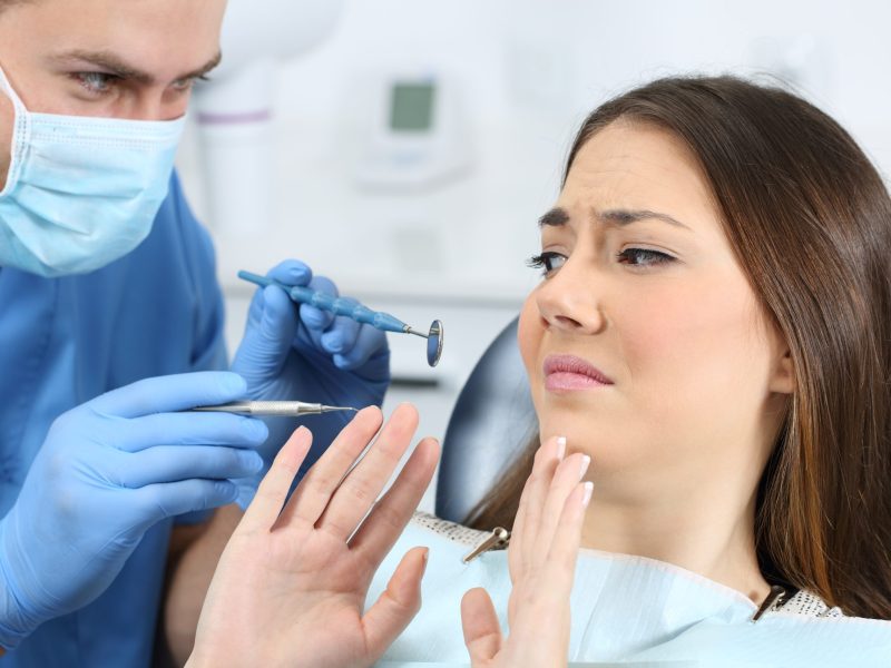 Anxious patient raising hands refusing dental examination
